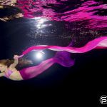 Mädchen mit Schwimmflosse in rosa schwimmt im Becken